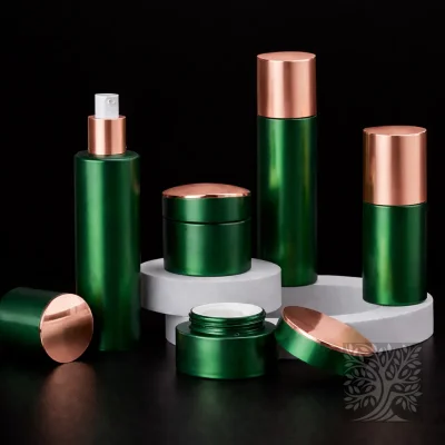 Metallic green cosmetic bottles and jars with rose gold accents, styled on white risers with an open cream jar.