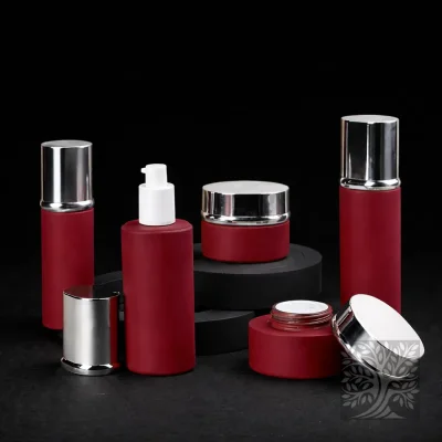 Deep red Torr bottles and cosmetic jars with silver caps, arranged on black platforms with polished lids scattered.
