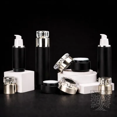 Gloss black skincare bottles and cosmetic jars with silver caps, arranged on white risers with matching lids.