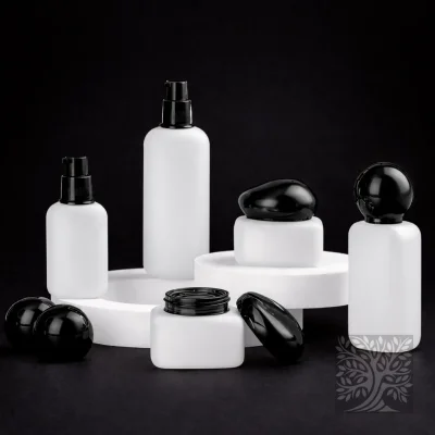 Frosted white glass skincare bottles and matching jars with black caps, arranged in a minimal high-contrast product layout.