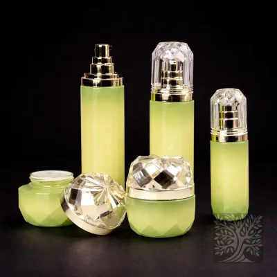Light green faceted glass skincare bottles and cosmetic jars with gold pumps and crystal-style caps, arranged in a Facet set.