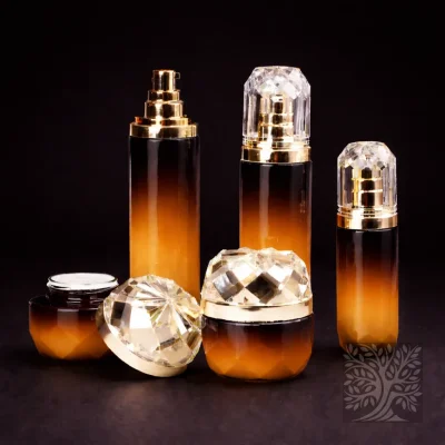 Amber gradient glass serum bottles and cosmetic jars with gold accents and faceted bases, displayed in a warm-toned set.