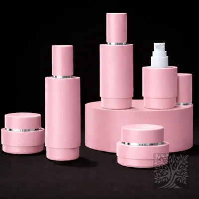 Soft pink skincare bottles and cosmetic jars with silver accents, including a pump bottle, arranged on a circular display platform.