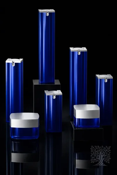 Gloss cobalt blue acrylic bottles and jars with silver caps, displayed with varying heights on black stands.