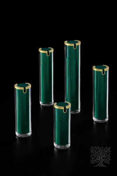 Deep green acrylic skincare bottles with gold caps and transparent outer walls, arranged in a modern product lineup.