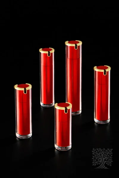 Rich red acrylic bottles with gold collars and clear outer layers, forming a cohesive luxury skincare packaging display.