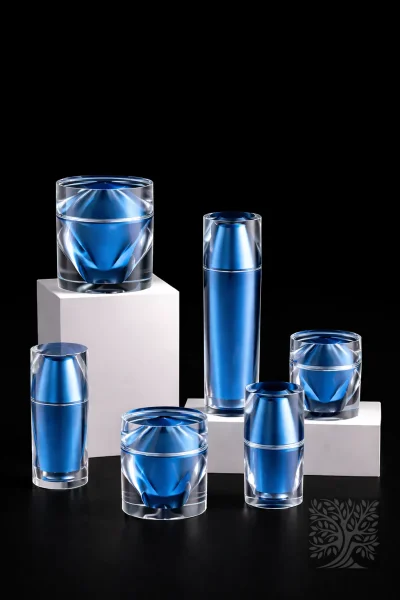 Metallic blue acrylic serum bottles and matching cream jars with angular faceted exteriors, styled in a modern packaging set.