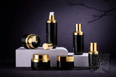 Black skincare bottles and cosmetic jars with glossy gold caps, arranged on white stands with a pump bottle and open jar.